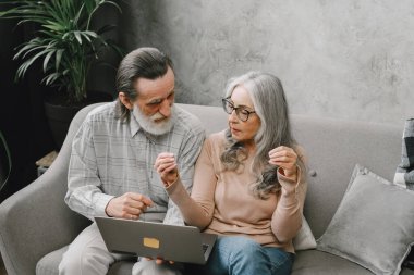 Üst düzey çift dizüstü bilgisayarlarıyla kanepede oturuyor.