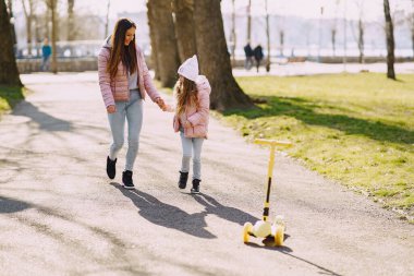 Anne ve kızı bahar parkında kayıyorlar.