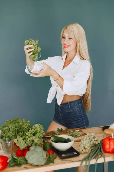 Menina bonita e desportiva em uma cozinha com um legumes — Fotografia de Stock