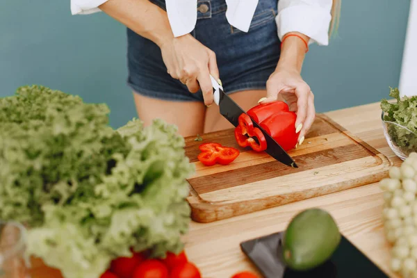 Krásná a sportovní dívka v kuchyni se zeleninou — Stock fotografie