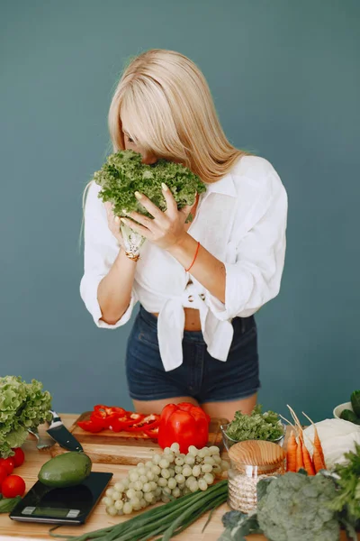 Beautiful and sporty girl in a kitchen with a vegetables — Stock Photo, Image