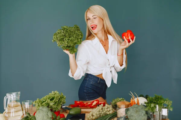 Beautiful and sporty girl in a kitchen with a vegetables — Stock Photo, Image