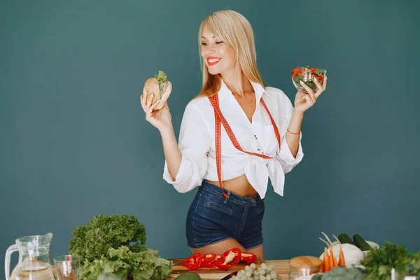 Beautiful and sporty girl in a kitchen with a vegetables — Stock Photo, Image