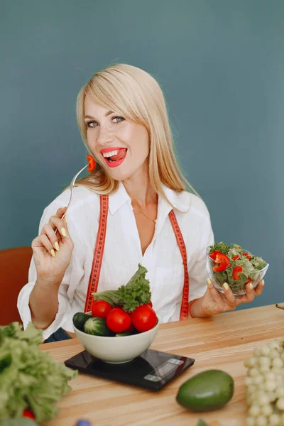 Beautiful and sporty girl in a kitchen with a vegetables — Stock Photo, Image