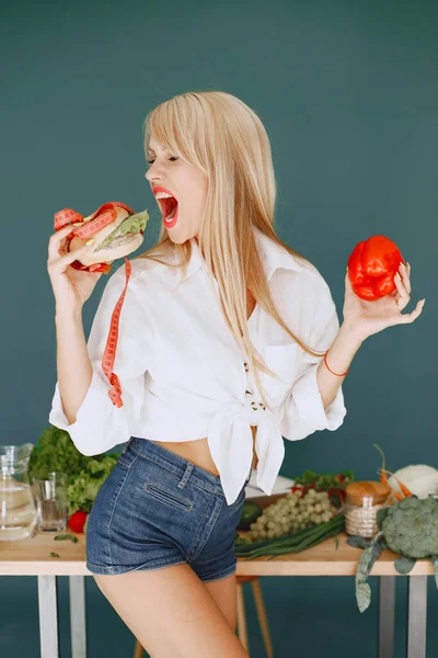 Beautiful and sporty girl in a kitchen with a vegetables — Stock Photo, Image