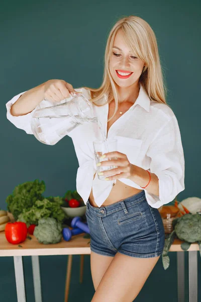 Beautiful and sporty girl in a kitchen with a vegetables — Stock Photo, Image