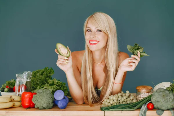 Menina bonita e desportiva em uma cozinha com um legumes — Fotografia de Stock