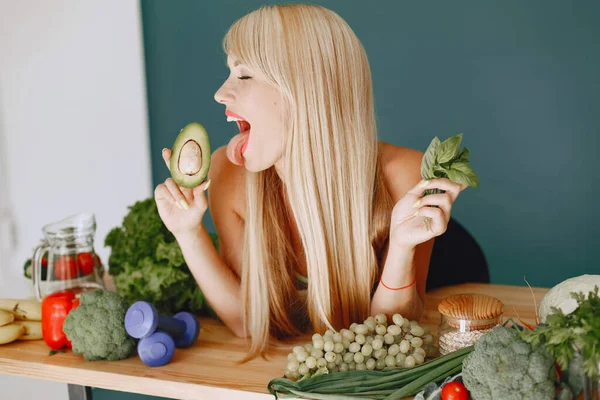 Beautiful and sporty girl in a kitchen with a vegetables — Stock Photo, Image