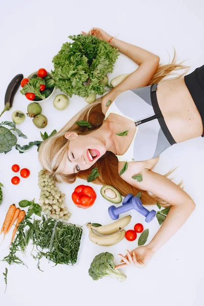 Beautiful and sporty girl in a kitchen with a vegetables — Stock Photo, Image