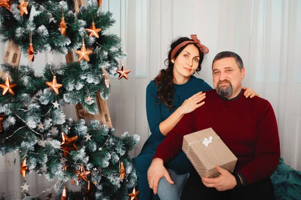 Família adulta sentada em casa perto da árvore de natal — Fotografia de Stock