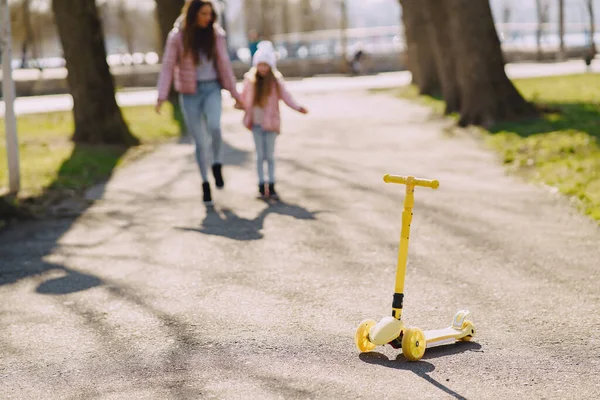 Mãe com filha em um parque de primavera com patins — Fotografia de Stock