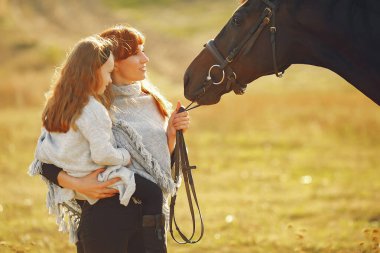 Anne ve kızı bir tarlada bir atla oynuyorlar.