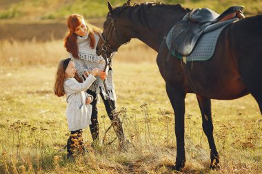Anne ve kızı bir tarlada bir atla oynuyorlar.
