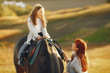 Anne ve kızı bir tarlada bir atla oynuyorlar.