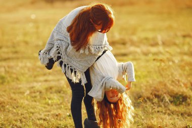 Anne ve küçük kızı sonbahar tarlasında oynuyorlar.