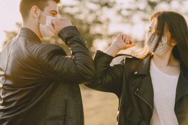 Bahar ormanında maskeli insanlar dikiliyor.