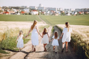 Sonbahar tarlasında kızlarıyla oynayan anneler.