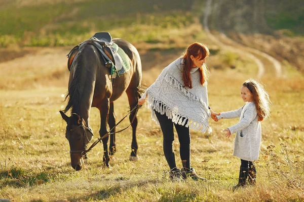 Mãe e filha em um campo brincando com um cavalo — Fotografia de Stock