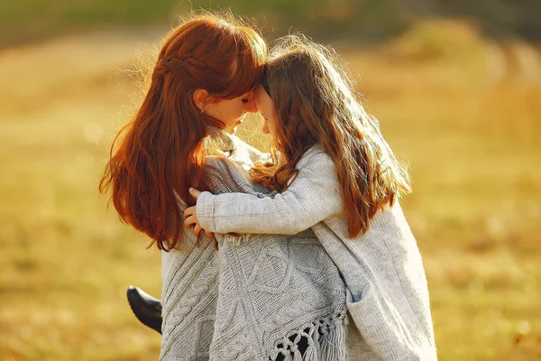 Mor med liten dotter som leker på ett höstfält — Stockfoto