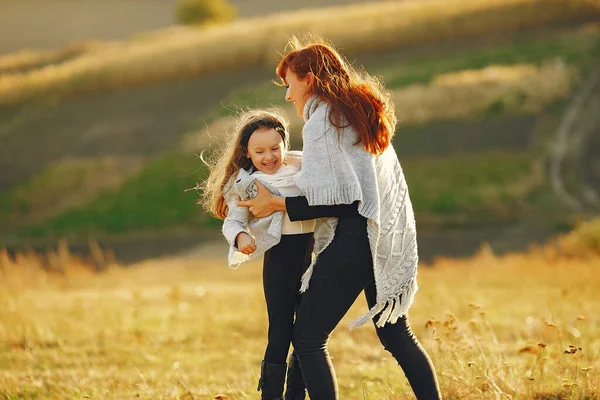 Мать с маленькой дочерью играет на осеннем поле — стоковое фото