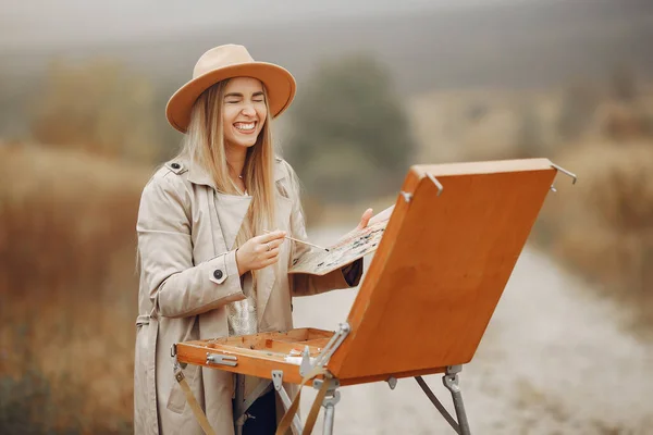 Donna in una pittura cappotto marrone in un campo — Foto Stock