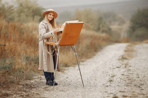 Kahverengi ceketli bir kadın tarlada resim yapıyor. — Stok fotoğraf