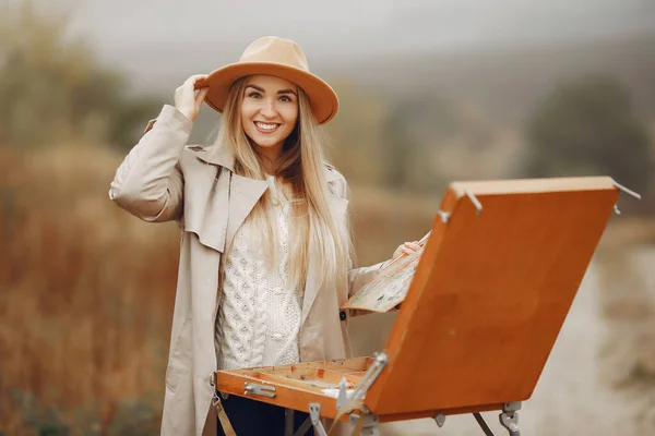 Donna in una pittura cappotto marrone in un campo — Foto Stock