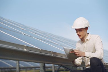 Güneş bataryasının yanında beyaz kasklı bir iş adamı.