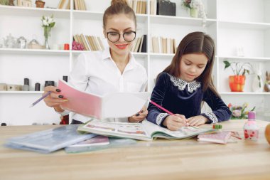 Küçük kızla evde ders çalışan bir öğretmen.