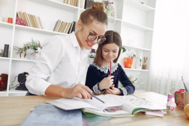Küçük kızla evde ders çalışan bir öğretmen.