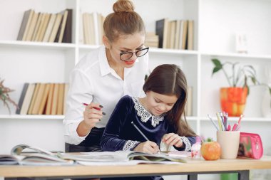Küçük kızla evde ders çalışan bir öğretmen.