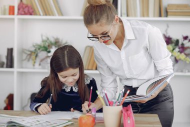Küçük kızla evde ders çalışan bir öğretmen.