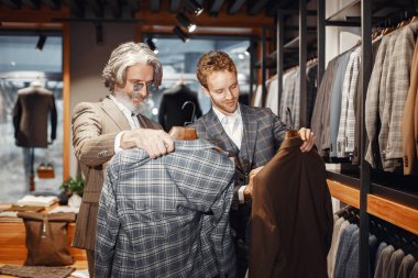 Üst düzey bir adam mağazadan yeni bir takım elbise seçiyor.
