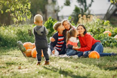 Balkabaklarının yanındaki bahçede oturan büyük bir aile.