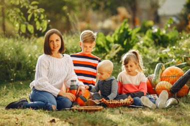 Balkabaklarının yanındaki bahçede oturan büyük bir aile.