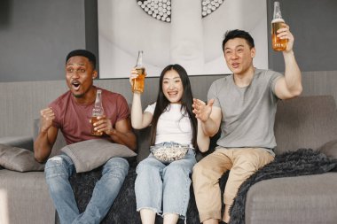 Üç arkadaş futbol izleyip bira içiyor.