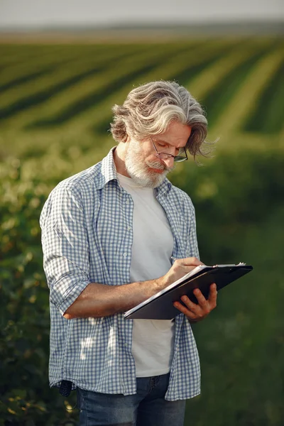 Old farmer in shirt standing on field with notebook — Stock Photo, Image