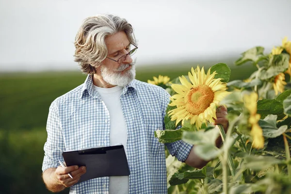 Antiguo granjero en camisa de pie en el campo con cuaderno —  Fotos de Stock