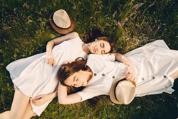 Retrato de duas irmãs em vestidos brancos com cabelo longo em um campo — Fotografia de Stock