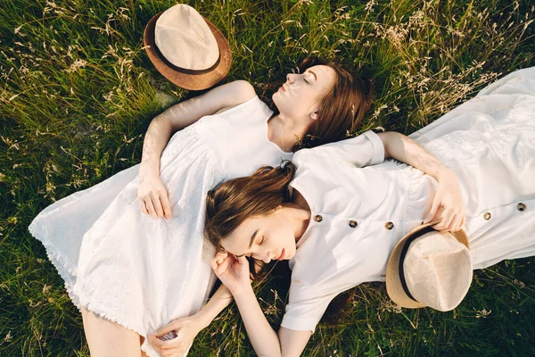 Portret dwóch sióstr w białych sukienkach z długimi włosami na polu — Zdjęcie stockowe