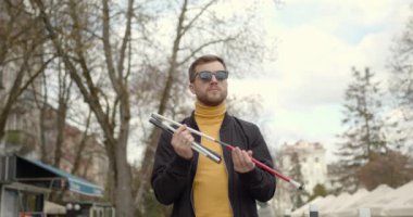Kör adam dışarıda baston kuruyor.