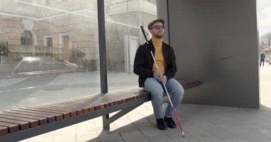 Şehirde bir bankta oturan kör adam.