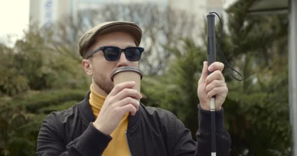 Hombre ciego sentado en el banco y bebiendo café — Vídeo de stock