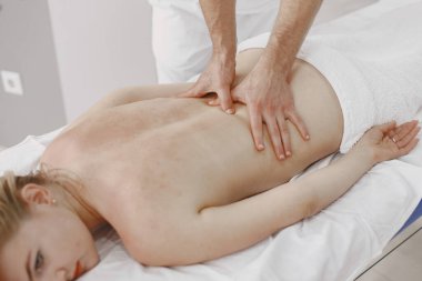 Erkek doktor kadın vücuduna masaj yapar.