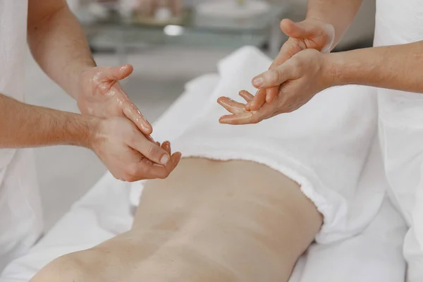 Quatro mãos fazem massagem ao corpo feminino — Fotografia de Stock