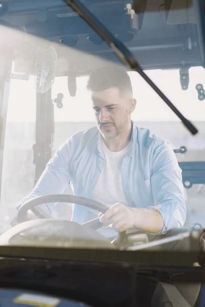 Hombre sentado cómodamente en un tractor azul grande —  Fotos de Stock