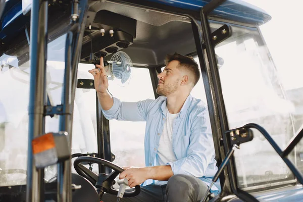 Hombre sentado cómodamente en un tractor azul grande —  Fotos de Stock