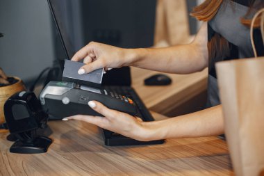 Kasiyer terminalden kredi kartıyla ödeme yapar. Kasiyer terminalden kredi kartıyla ödeme yapar..