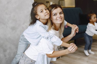 Mutlu anne ve sevimli küçük kız gülümseyip kameraya bakıyor. Çocuğu kucaklayan anne sırt üstü yatıyor..