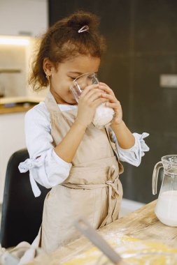 Mutfakta bir çocuk. Parası olan küçük bir kız. Bej önlüklü çocuk.